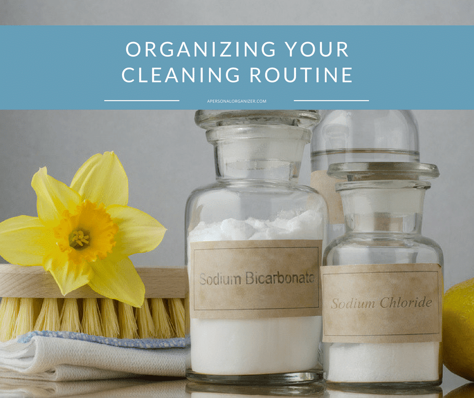 A cleaning supplies setup featuring glass jars labeled "Sodium Bicarbonate" and "Sodium Chloride," a yellow daffodil, a wooden cleaning brush, and a lemon. Text above reads "Organizing Your Cleaning Routine." Perfect tools to simplify your cleaning routine with natural ingredients.