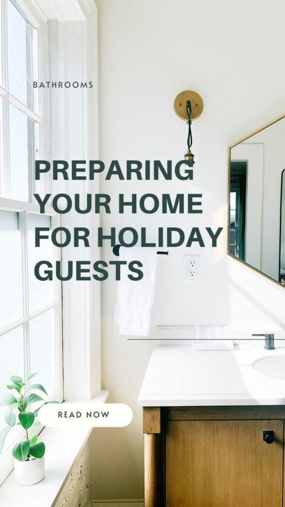 Bright, organized bathroom with a wooden vanity, a white countertop, and a modern faucet. A round mirror is above the sink, with a single towel on a hook. A small plant sits by the window. Text reads: "Preparing Your Home for Holiday Guests.