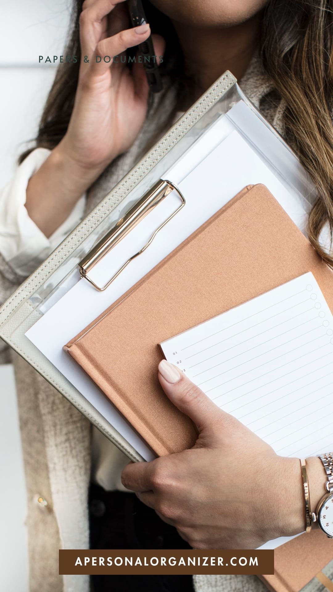 A person holds a clipboard, a brown notebook, and lined paper while talking on the phone. Text reads “Papers & Documents” and “apersonalorganizer.com”—reminding you to protect personal information when organizing documents.