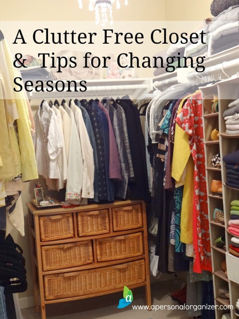 An organized, clutter-free closet filled with neatly hung clothing and items on shelves. Woven baskets are stacked on a rack below the hanging clothes. The text overlay reads, "A Clutter Free Closet & Tips for Changing Seasons" with a website URL at the bottom.