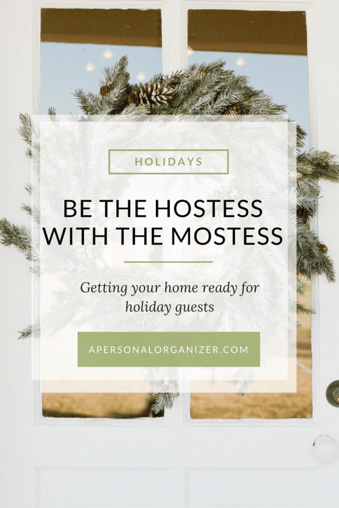 Festive wreath on a white door with text overlay: "Holidays - Be The Hostess With The Mostess - Getting your home ready for the holidays and welcoming guests. Apersonalorganizer.com.