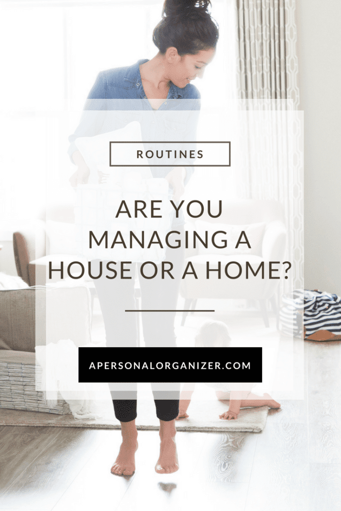 A woman stands in a tidy living room organizing items, exemplifying excellent home management. She looks down while a baby crawls on the floor near her. The text overlay reads, "ROUTINES. Are you managing a house or a home? apersonalorganizer.com." The room features neutral decor with modern and cozy elements.