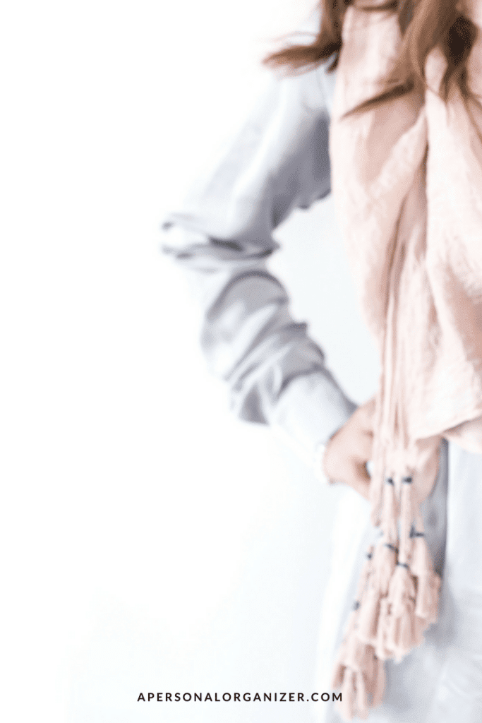 A person clad in a light-colored scarf and soft-toned clothes. Only the torso and part of the arm are visible. The image has a clean, minimalistic background, evoking a sense of calm amidst decluttering overwhelm. The text "APERSONALORGANIZER.COM" is displayed at the bottom.
