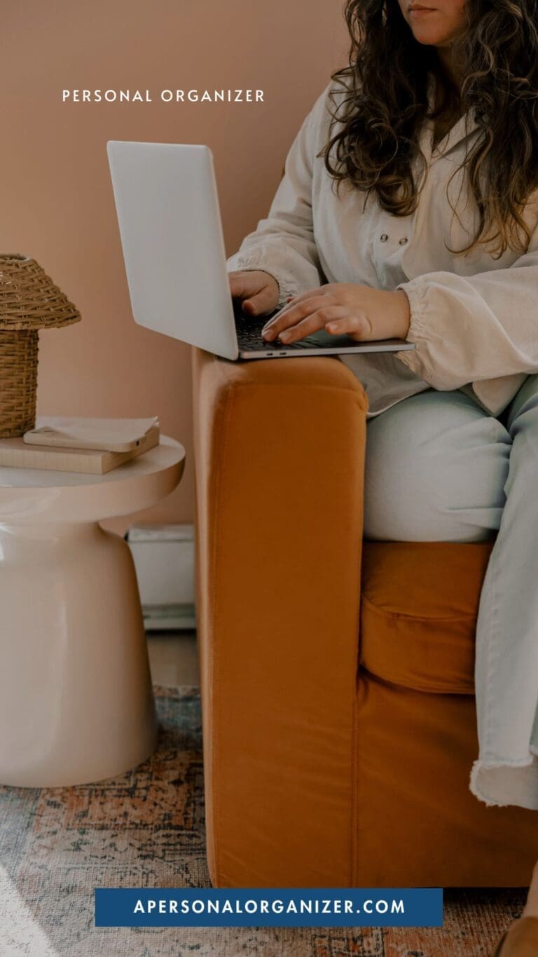 A woman sits on an orange chair using a laptop on her lap. Nearby, a small table holds books and a woven lamp—perfect for inspiring you to declutter your space. Text reads "Personal Organizer" and "apersonalorganizer.com.