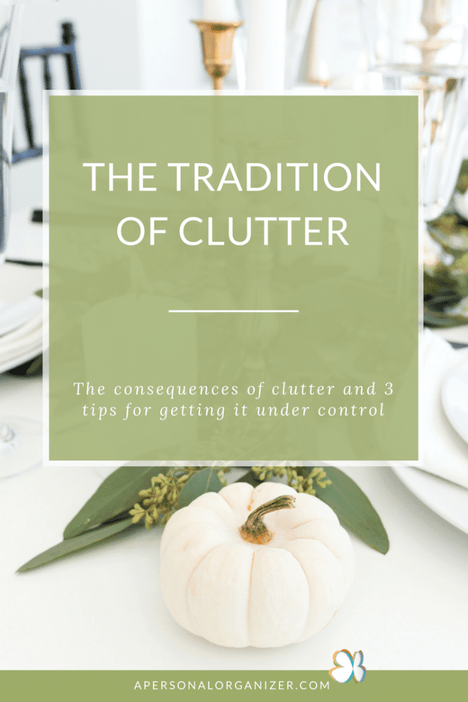 A decorative sign on a table reads "The Tradition of Clutter: The consequences of clutter and 3 tips for getting it under control." In the foreground, a small white pumpkin rests on greenery, while the blurred dining setup with candles and glassware hints at an organized space free of clutter.