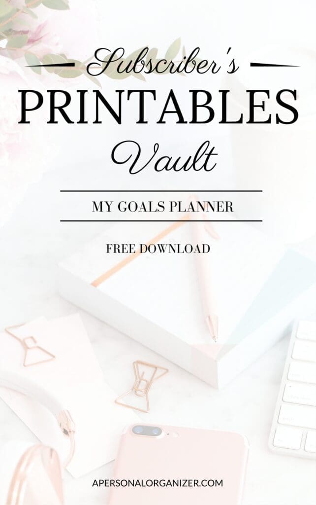 A promotional image for a "Subscriber's Printables Vault" offering free printables, including a goals planner download. The background features office supplies like a notebook, pen, paper clips, and a smartphone on a white desk.