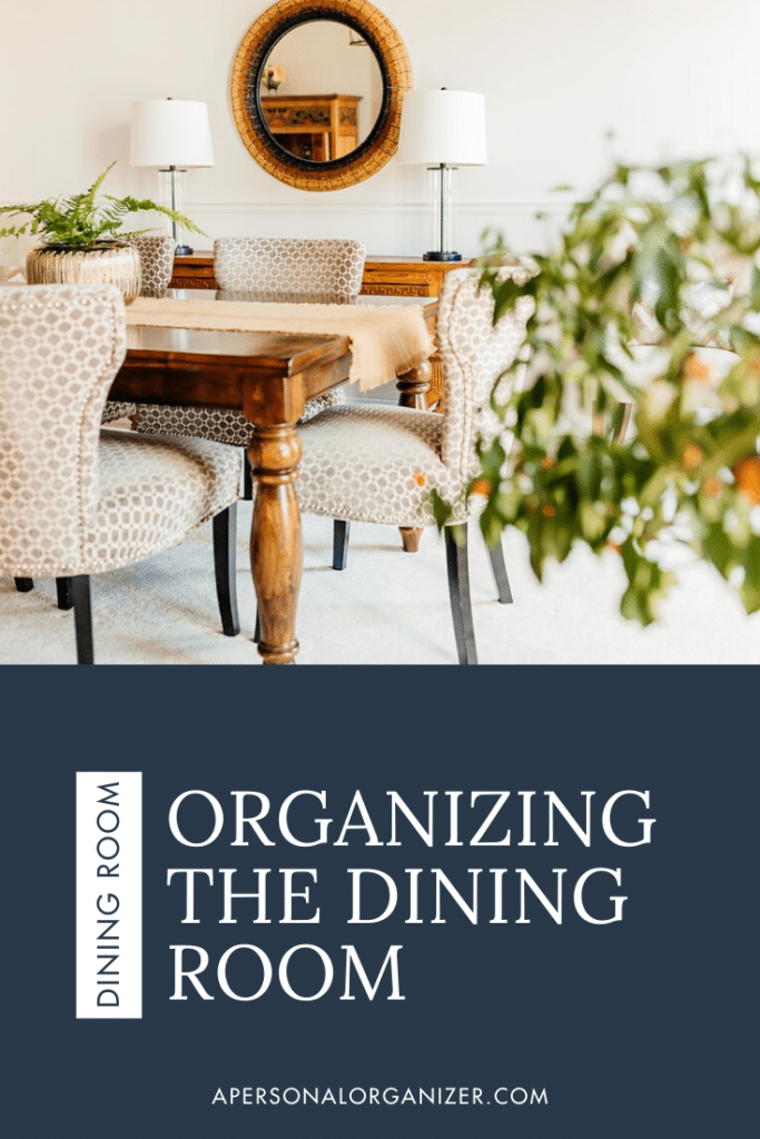 Elegant dining room with patterned chairs around a wooden table. A round mirror and plants adorn the space, creating an inviting atmosphere. Text overlay reads, "Organizing the Dining Room," offering tips for transforming this central home space at apersonalorganizer.com.