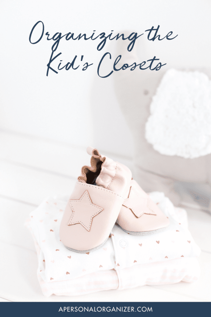 Baby shoes with star designs rest on folded clothes adorned with little hearts. Above, the text reads "Organizing Kids' Closets," a charming nod to how seamlessly you can organize kids' rooms. A soft, plush item cozily adds warmth in the background. Visit apersonalorganizer.com below.