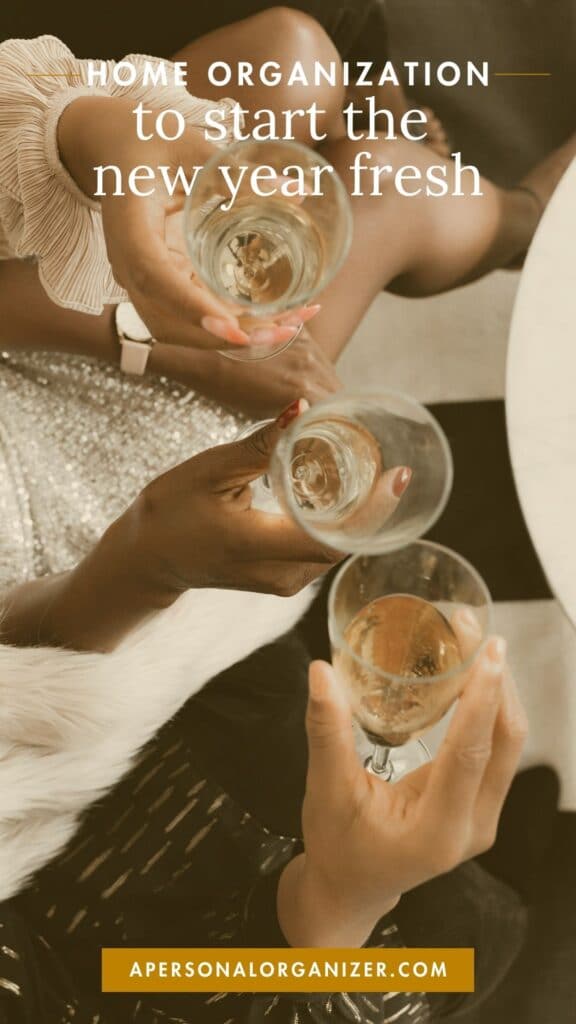 Three people clink champagne glasses over a marble table. The text reads, "Home organizing to start the new year fresh." Below, a website URL is shown. They wear festive outfits, suggesting a celebratory occasion.