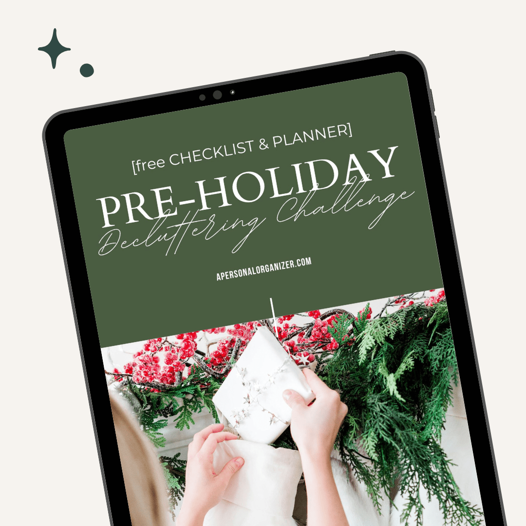 A tablet showcases an "Organizing Pre-Holiday Decluttering Challenge" with a checklist and planner. The screen, set against a green background, features hands wrapping a white gift adorned with evergreen and red berry accents. The website name is elegantly displayed at the bottom.