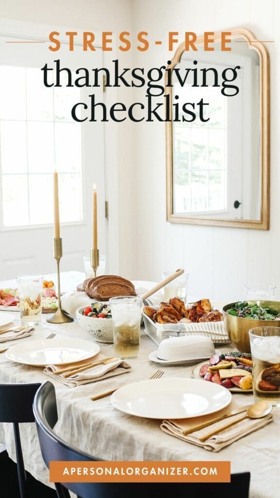 A dining table set for Thanksgiving adorned with plates, festive salads, bread, and glowing candles. "Stress-Free Thanksgiving Checklist" graces the top. A mirror and windows enhance the room's warmth.