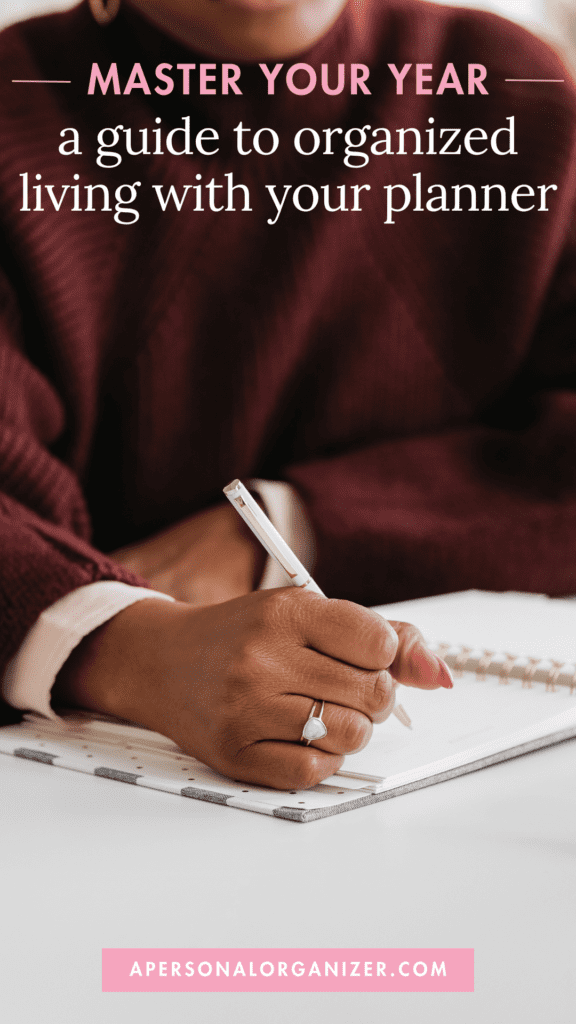 A person wearing a maroon sweater writes in a planner with a pen. The text on the image reads, "Master Your Year: a guide to organized living with your planner." The website "apersonalorganizer.com" is displayed at the bottom.