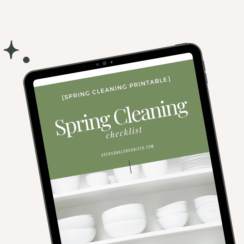 A tablet displays an "Organizing Spring Cleaning" checklist with a green header and "apersonalorganizer.com" below. The screen shows white dishes neatly arranged on shelves, emphasizing organization. A small decorative star sits on the left, enhancing the tidy aesthetic.