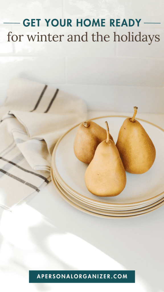 Three pears sit on a stack of white plates with a striped cloth nearby. The text at the top reads, "Organize Your Home for Winter Holidays," and at the bottom, "apersonalorganizer.com.