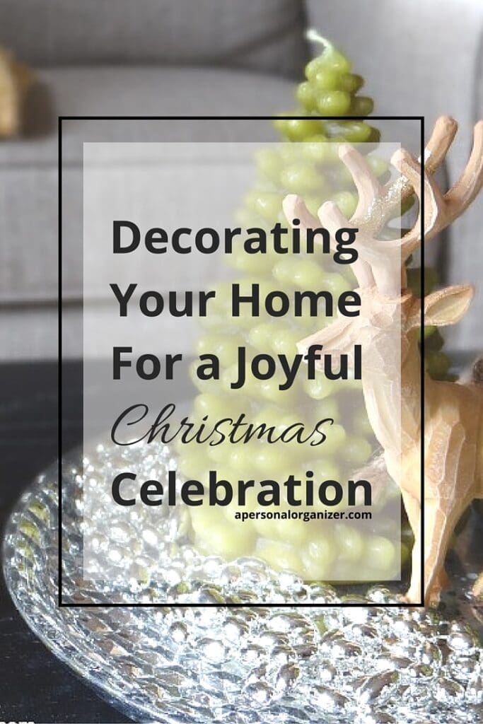 A decorative tray with a green Christmas tree candle and a wooden reindeer figurine sits on a table, creating charming christmas decorations. Text over the image reads, "Decorating Your Home for a Joyful Christmas Celebration.