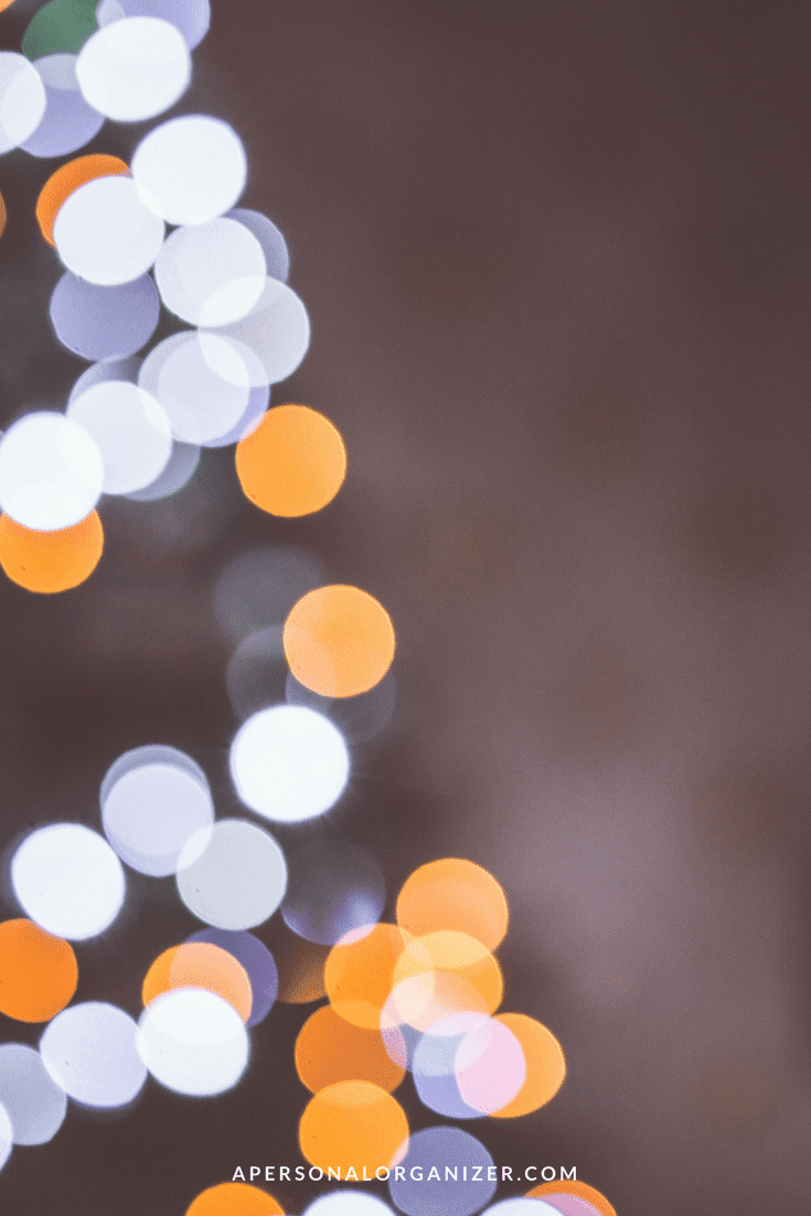 A blurred image of glowing lights in circular shapes of various sizes, predominantly in white and orange hues, set against a muted background. The text "APERSONALORGANIZER.COM" is displayed at the bottom center of the image, offering a subtle reminder to feng shui your holidays.