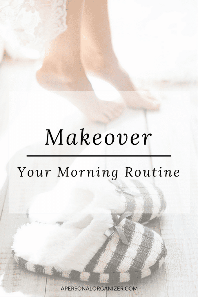 A pair of plaid slippers sits on a wooden floor. Above the slippers, the text reads "Makeover Your Morning Routine." In the blurred background, a person's feet are visible as they stand on a soft white surface, emphasizing how these slippers can elevate your morning routine.