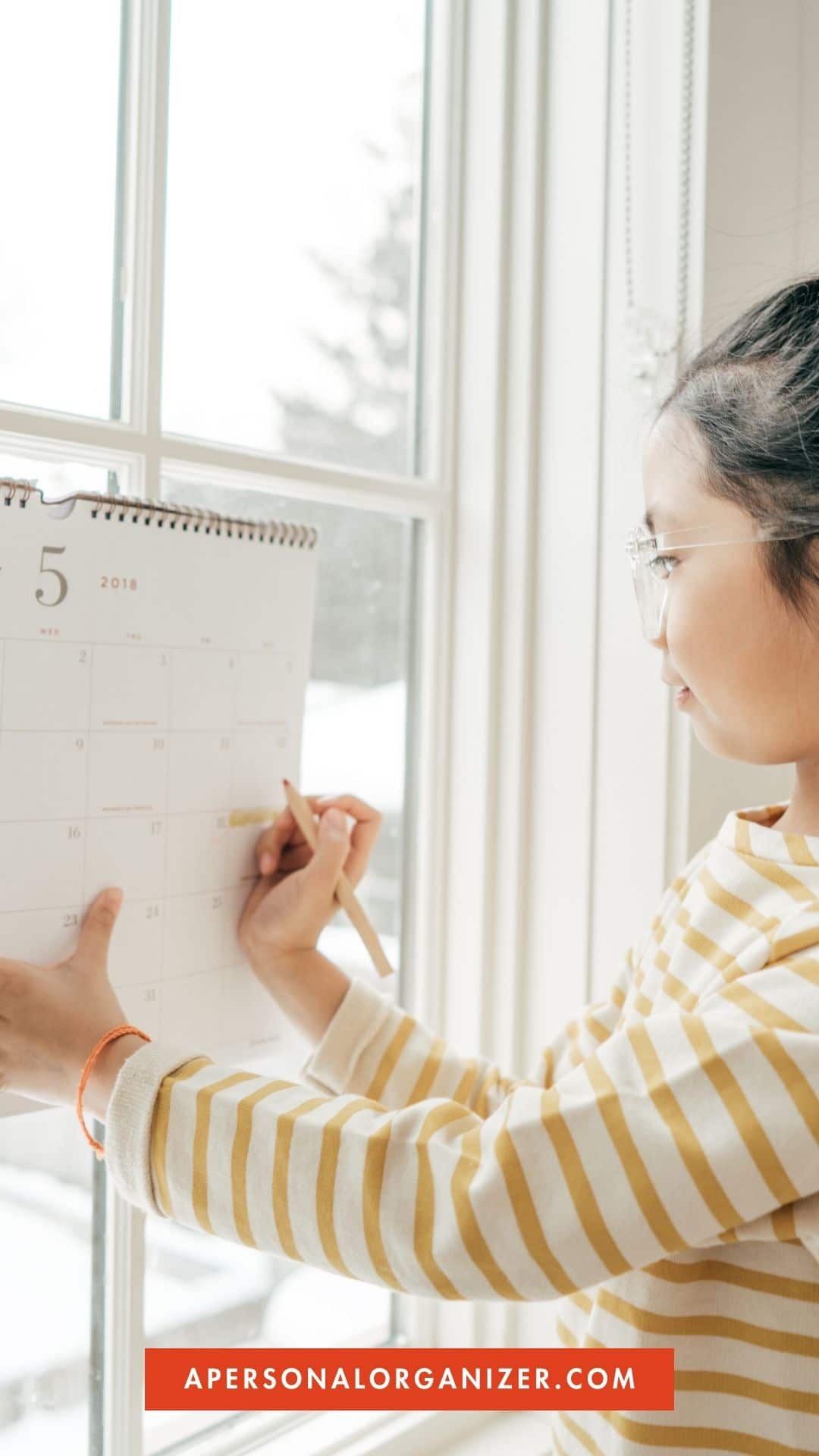 girl writing on a wall calendar
